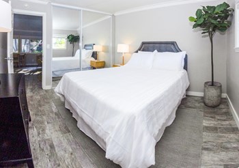 Image of a bedroom with a queen size bed, dresser, and mirrored closet doors